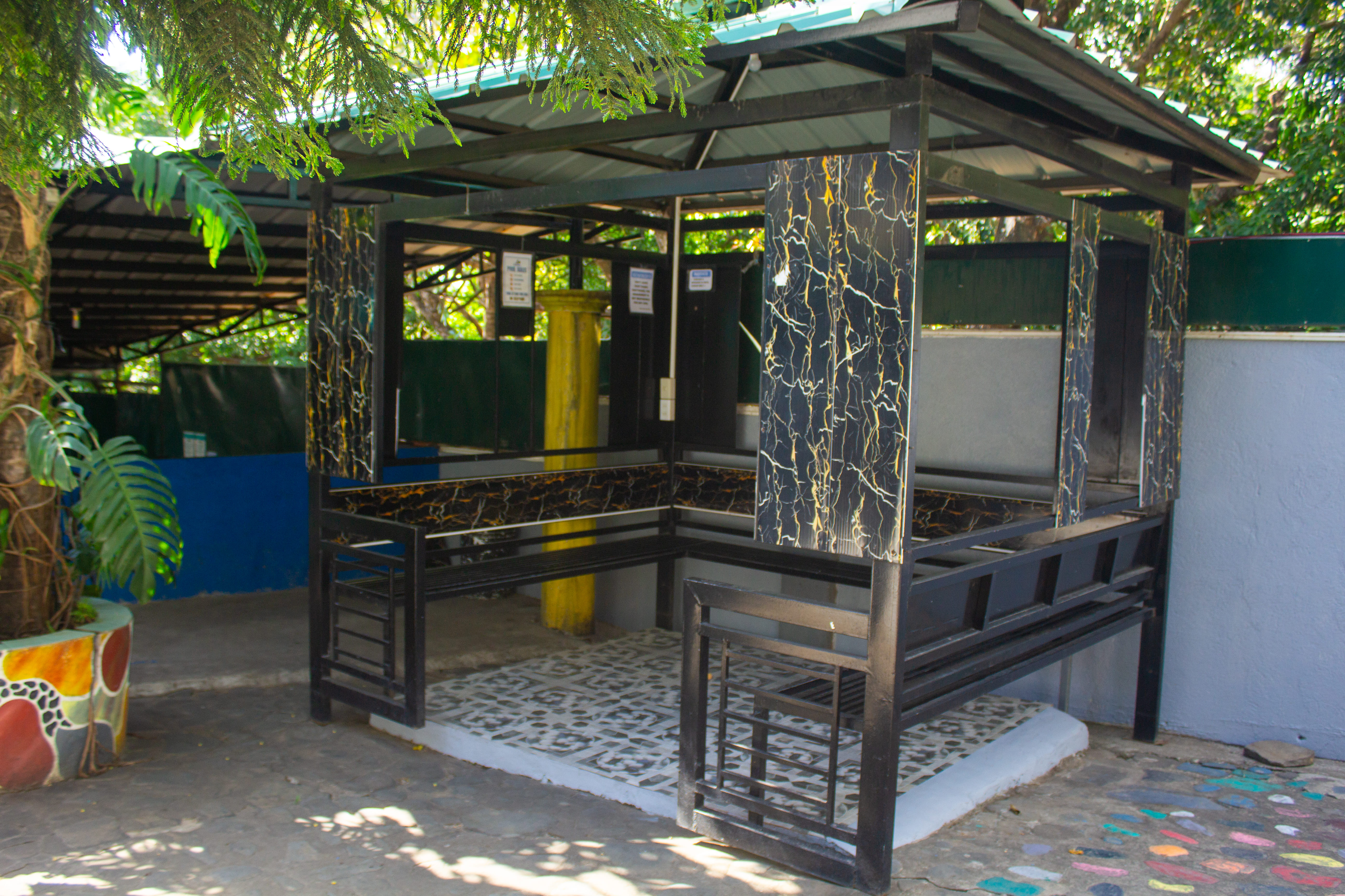 Modern outdoor cabana with black and gold marble-like panels, a built-in seating area, and a metal roof.