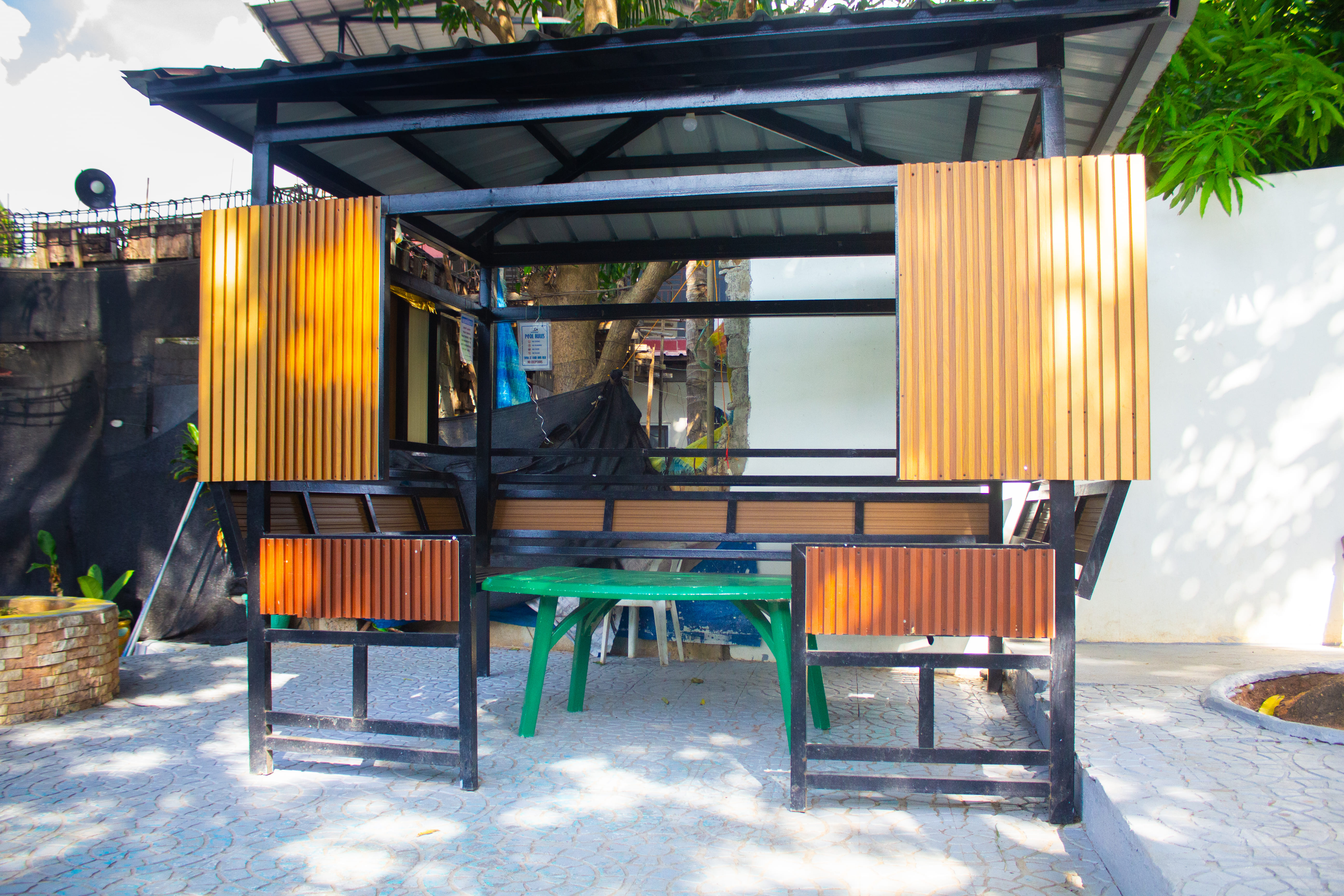 Cozy poolside cabana with wooden furniture and curtains.