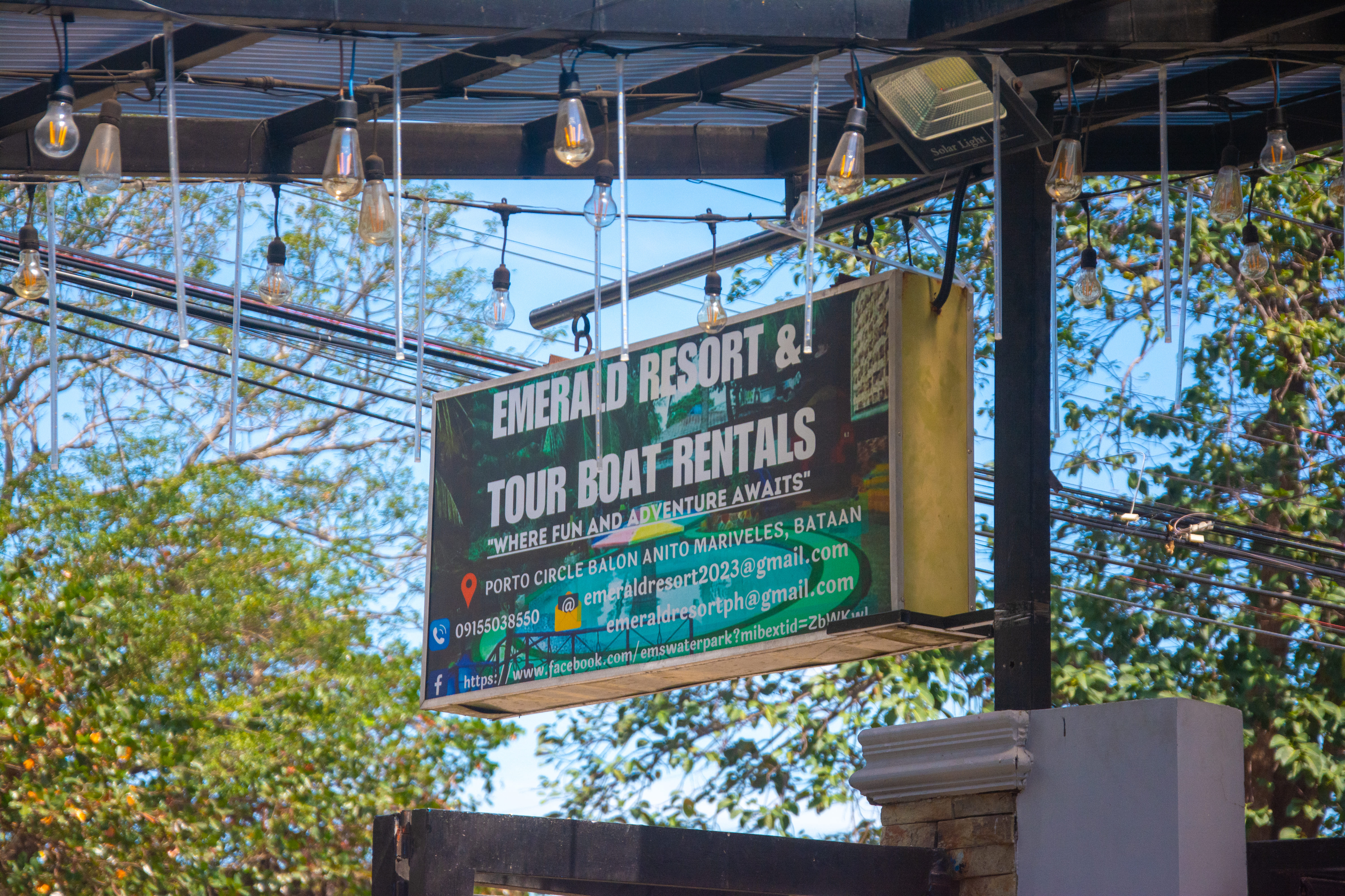 Emerald Resort signage surrounded by lush greenery and a clear blue sky.